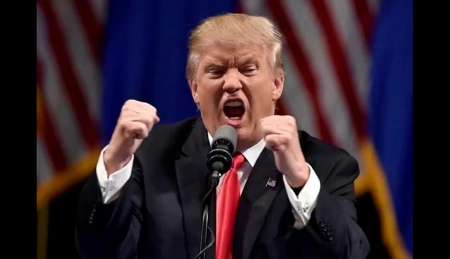 Donald Trump holding a microphone and singing with fists raised in front of American flags