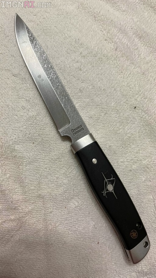 A silver Eduard Albani knife with a black handle and geometric inlay lying on a white paper towel.