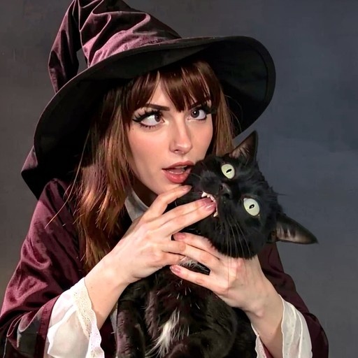A woman in a witch costume holds a black cat with bared teeth near her face against a grey background.