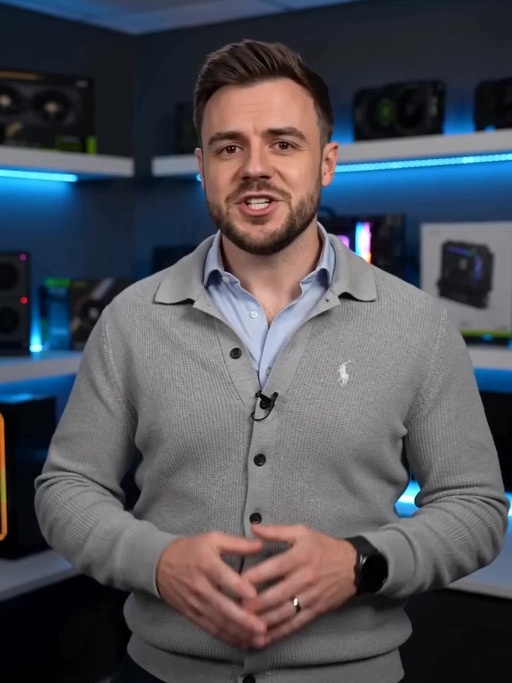 A well-groomed British male tech presenter in smart-casual attire speaks directly to the camera while discussing high-end graphics cards, accompanied by rapid cuts of cinematic product shots and on-screen price overlays for the Zotac RTX 5090 Solid and Gigabyte RTX 5090 Aorus Infinity.