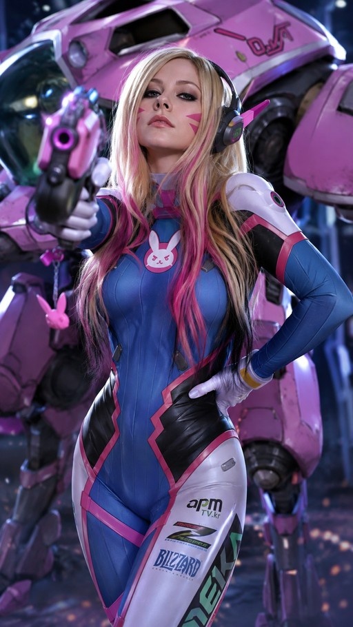 A woman cosplaying as D.Va from Overwatch stands in a blue and white bodysuit holding a pink gun, with a large pink mech suit behind her.
