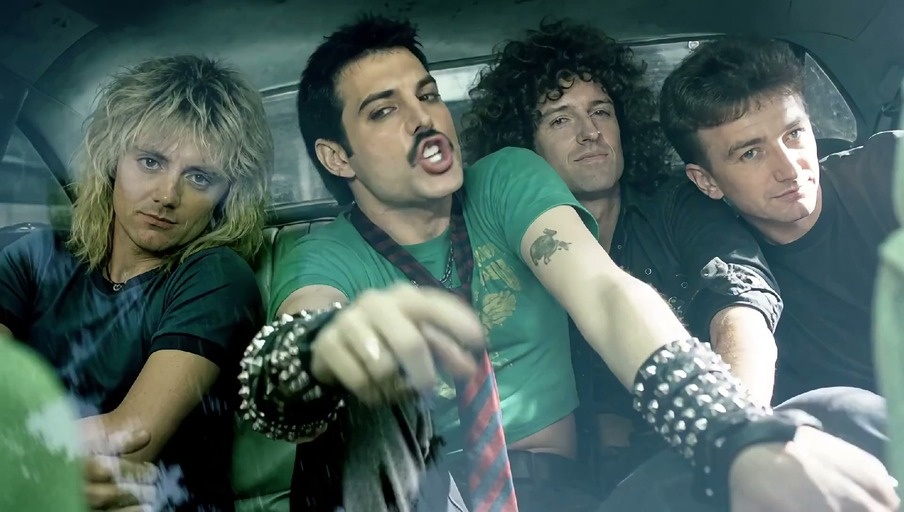 Freddie Mercury sings into a microphone while driving with Queen bandmates and later performs on a smoky stage.